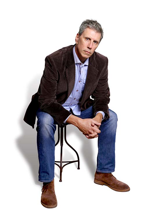 Photo of David Deal seated on a white background.